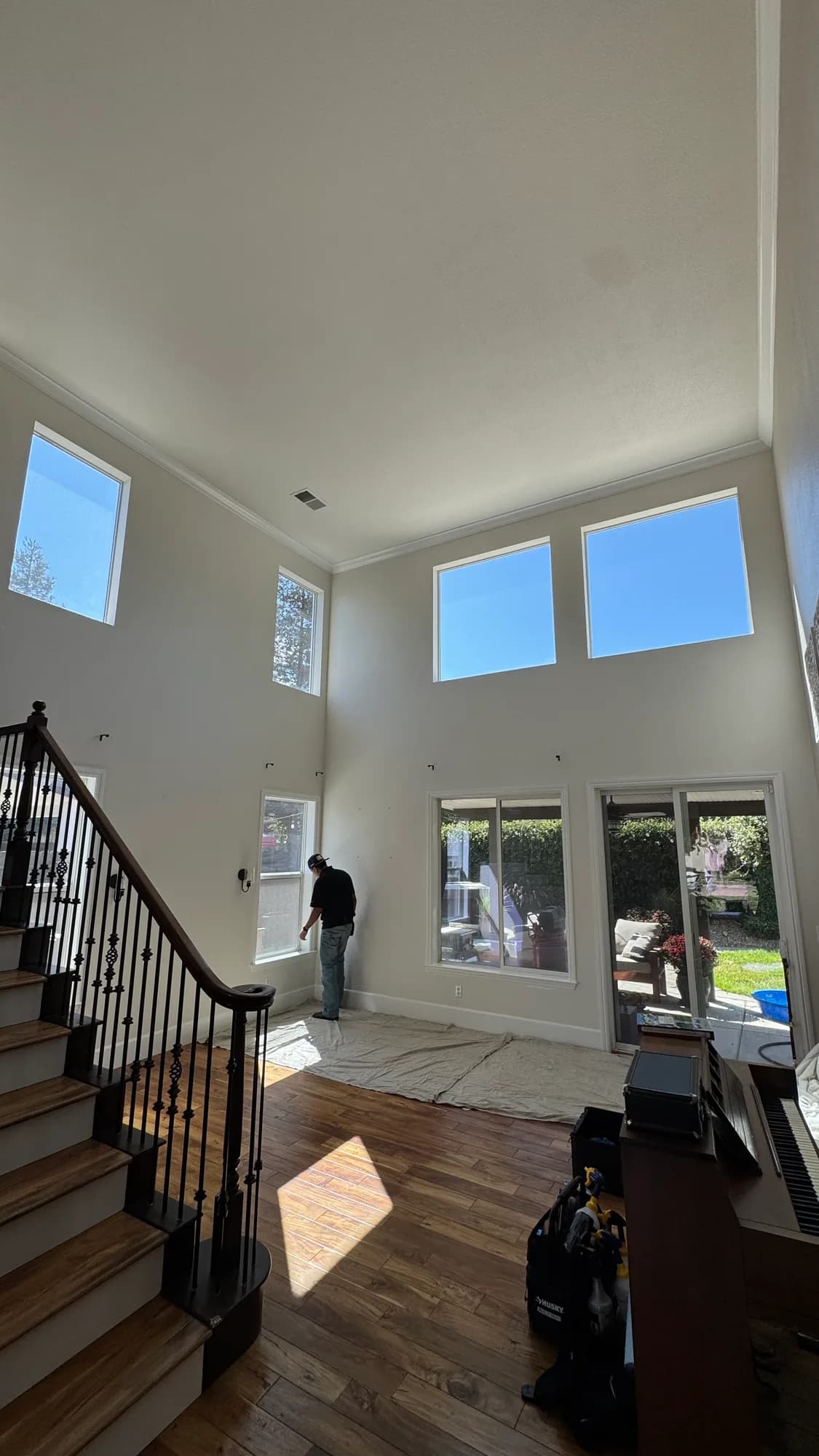 Two-story great room in a Ripon CA home with high windows being fitted with heat-control window film